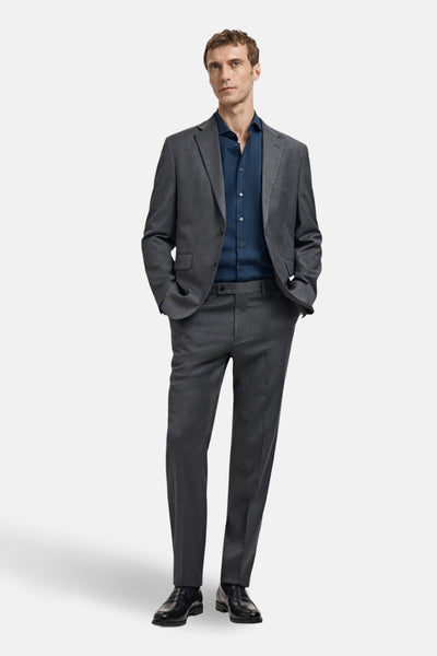 Chemise à manches longues bleue de MANGO, portée avec un costume gris et des chaussures noires.