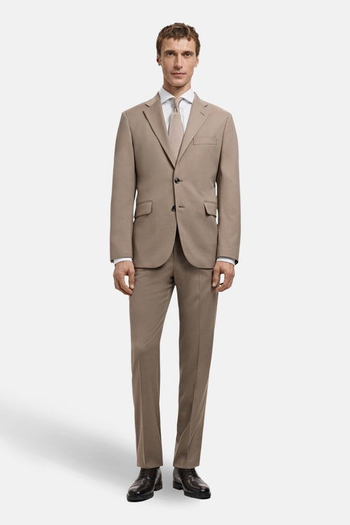 Chemise blanche à manches longues par MANGO, portée sous un costume beige uni avec une cravate assortie et des chaussures noires.
