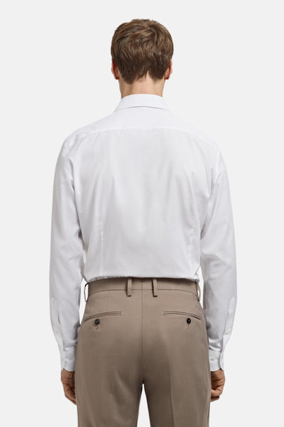 Chemise à manches longues blanche de MANGO, vue de dos, portée avec un pantalon beige.