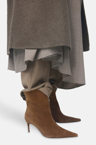 Bottines marron en cuir suédé de MANGO, portées avec un pantalon beige et des vêtements multicouches.