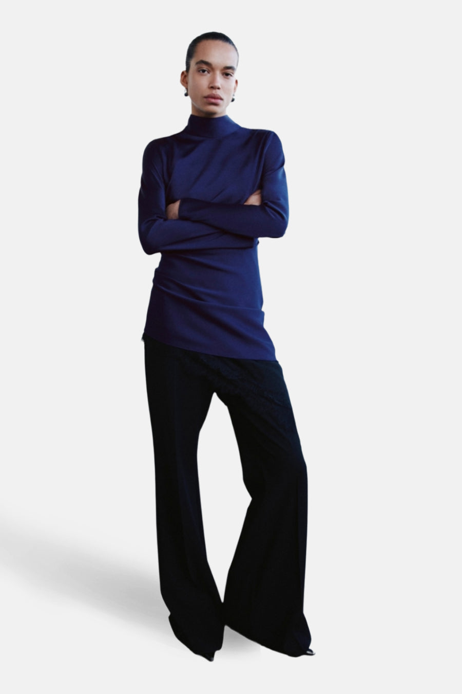 Blauwe jurk van MANGO, met een opstaande kraag en een nauwsluitende pasvorm, gedragen met een wijde zwarte broek.