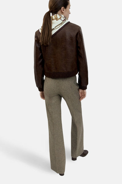 Veste courte brun de MANGO en similicuir à motif crocodile portée avec pantalon à carreaux.