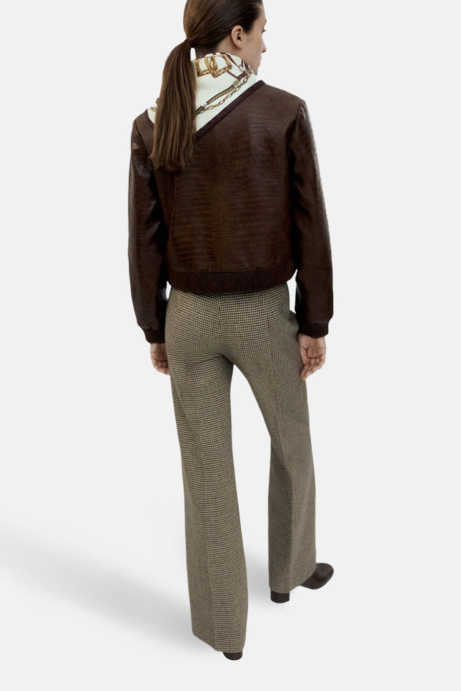 Veste courte brun de MANGO en similicuir à motif crocodile portée avec pantalon à carreaux.