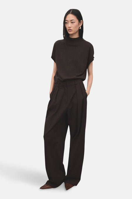 Pull à col rond brun de MANGO, porté avec un pantalon taille haute et des chaussures pointues.