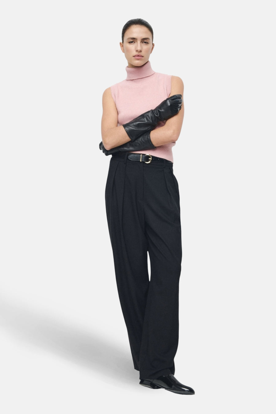 Roze hemdje van MANGO, gedragen met zwarte handschoenen, een wijde broek met hoge taille en lakleren schoenen.
