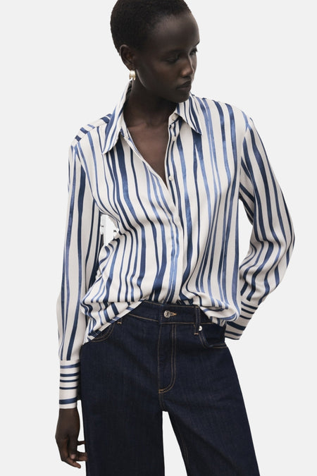 Chemisier à manches longues multicolore de MANGO, à rayures verticales bleues et blanches, porté avec un jean foncé.
