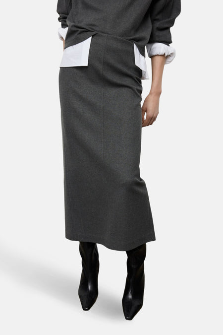 Jupe longue grise par MANGO, avec une chemise blanche et des bottes noires.