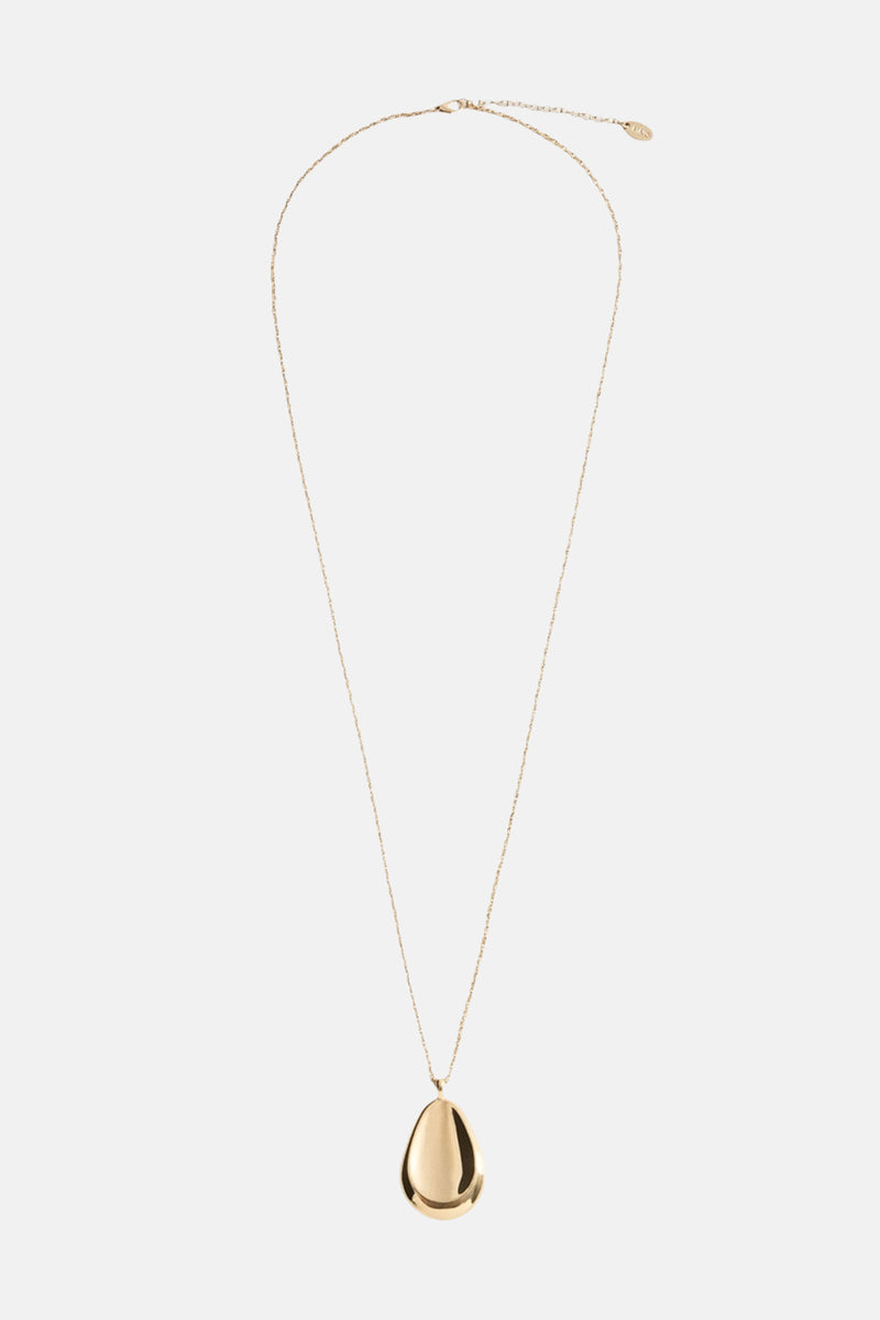 Lange gouden ketting van MANGO, gedragen met een geribbelde trui en een imitatiebontjas.