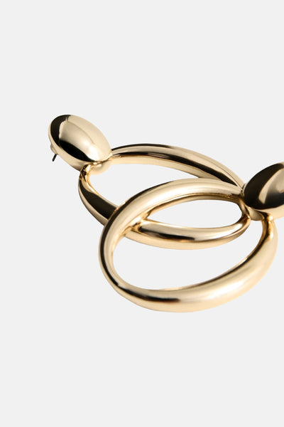 Gouden oorbellen van MANGO, bestaande uit twee in elkaar grijpende cirkels en een knoopsluiting.