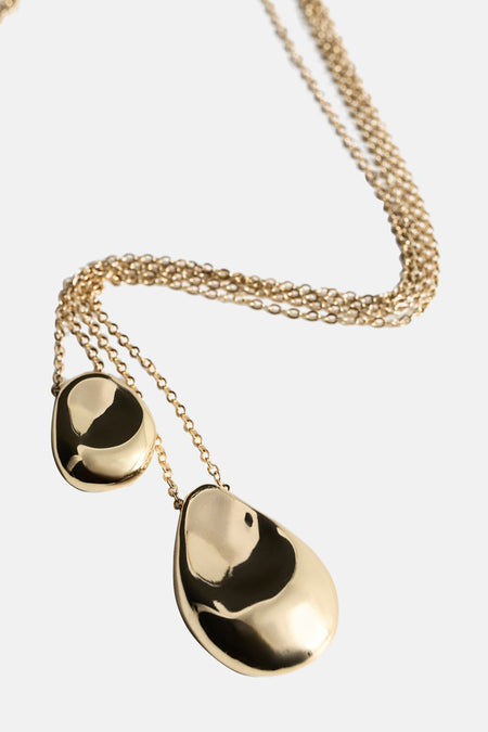 Collier court doré de MANGO, avec deux breloques aux formes organiques et réfléchissantes.