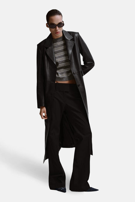 Pull à col rond gris de MANGO, rayures horizontales, porté avec un manteau noir et un pantalon taille haute.