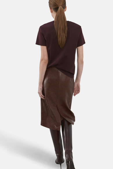 T-shirt bordeaux à manches courtes de MANGO, porté avec une jupe marron texturée et des bottes assorties, vue de dos.