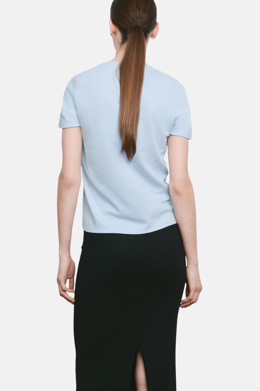 T-shirt bleu à manches courtes de MANGO, porté avec une jupe noire fendue au dos.