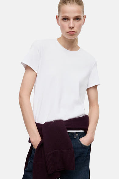 Wit T-shirt met korte mouwen van MANGO, achterkant, gedragen met een wijde spijkerbroek met omslag.
