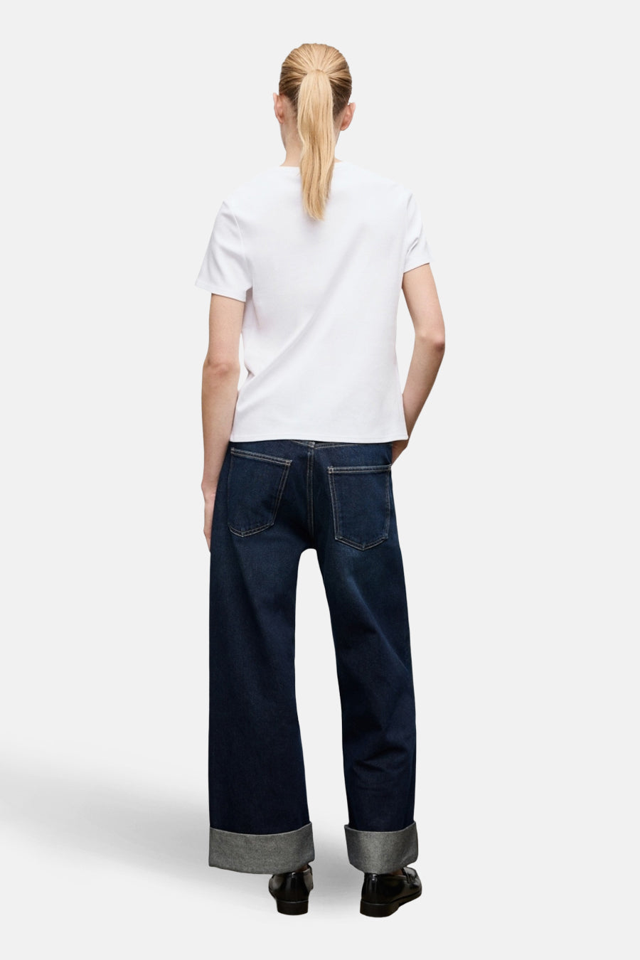 T-shirt blanc à manches courtes de MANGO, vue de dos, porté avec un jean bleu ample à revers.