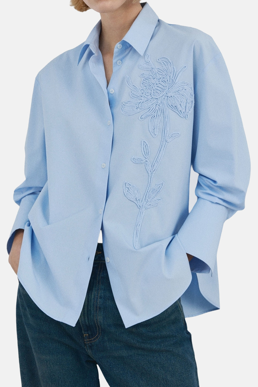 Blauwe blouse met lange mouwen van MANGO, met plooien aan de achterkant, gedragen met een wijde spijkerbroek en bruine schoenen.