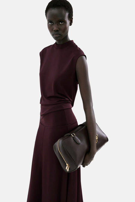 Top sans manches bordeaux de MANGO, porté avec une jupe longue assortie et un sac à main structuré marron.