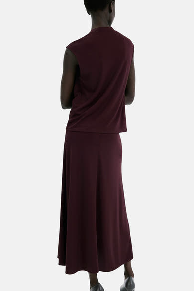 Top bordeaux sans manches de MANGO, porté avec une jupe longue de couleur assortie, vue de dos.
