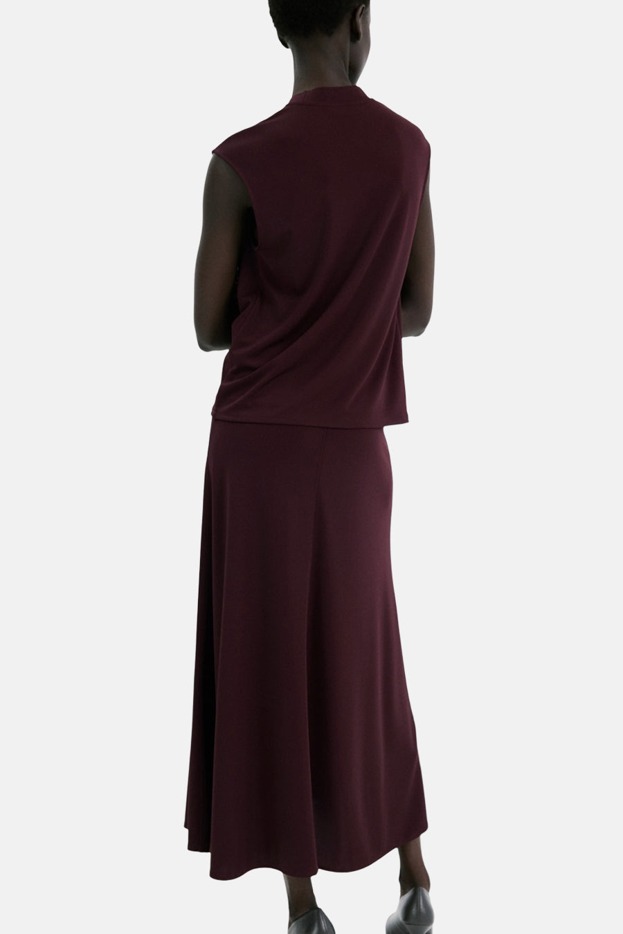 Top bordeaux sans manches de MANGO, porté avec une jupe longue de couleur assortie, vue de dos.
