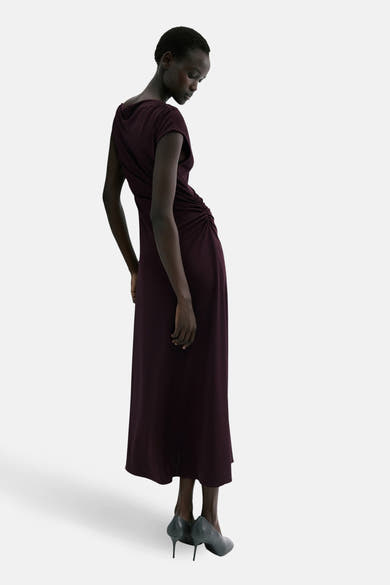 Bordeauxrode jurk van MANGO, gedrapeerd aan de zijkant met een asymmetrische snit.