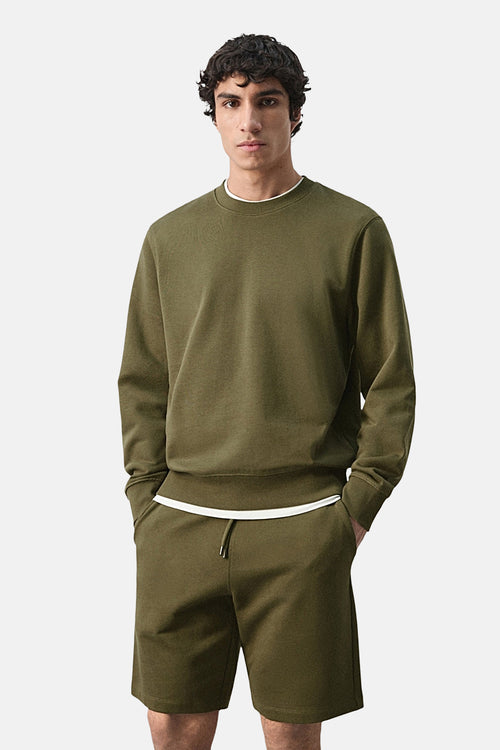 Sweat-shirt kaki de MANGO, avec un col rond et porté avec un short assorti.