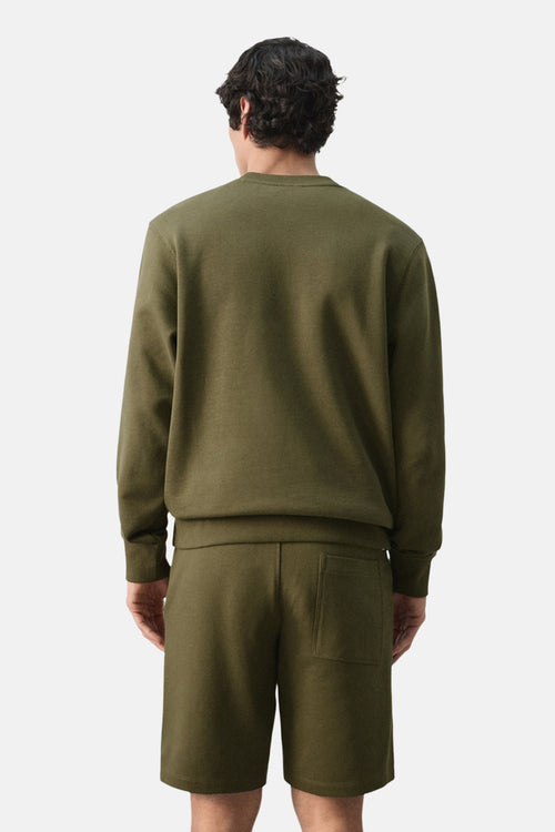 Sweat kaki de MANGO, avec manches longues et coupe droite, porté avec un short assorti, vue de dos.