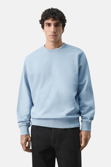 Sweat-shirt bleu de MANGO, porté avec un pantalon noir, coupe classique et manches longues.
