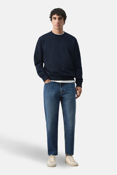 Zwarte rondehals sweatshirt van MANGO, gedragen met een wit T-shirt en een blauwe jeans.