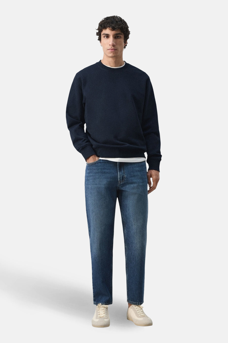Zwarte rondehals sweatshirt van MANGO, gedragen met een wit T-shirt en een blauwe jeans.