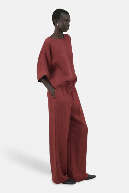 Blouse à manches courtes brune de MANGO, en tissu texturé, portée avec un pantalon assorti.