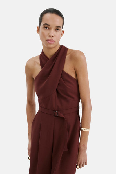 Combinaison brune par MANGO, avec un col drapé croisé, une ceinture et un bracelet doré.
