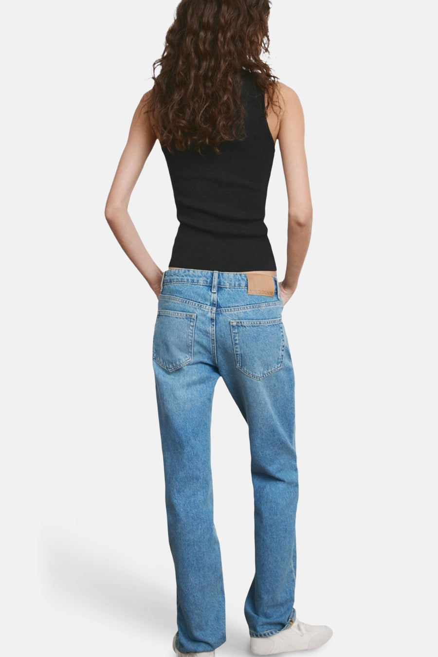 Débardeur noir, par MANGO, porté avec un jean bleu et des baskets blanches, vue de dos.