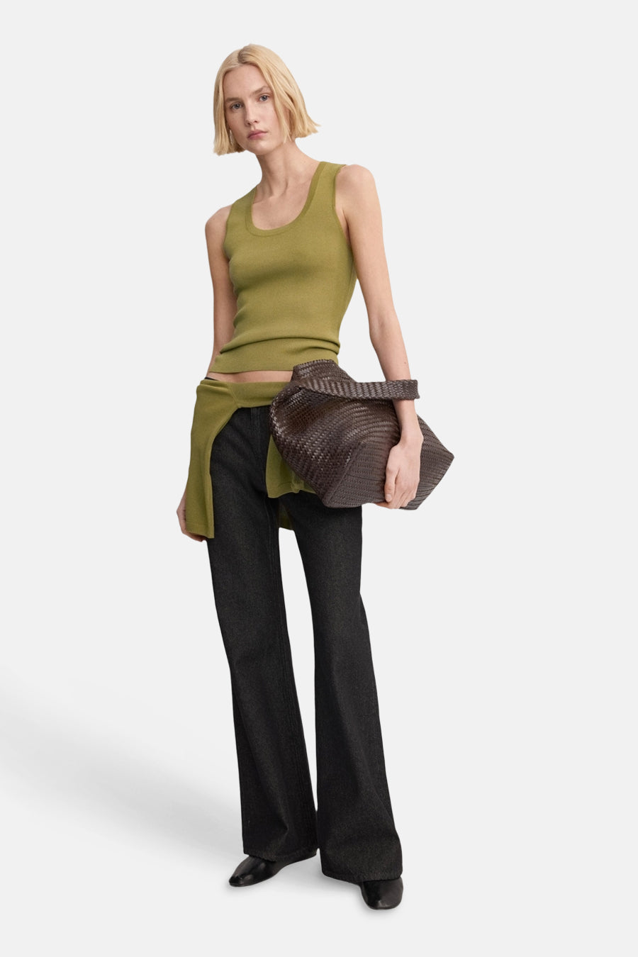 Débardeur kaki de MANGO, porté avec un pantalon évasé foncé et un sac à main en cuir tressé.