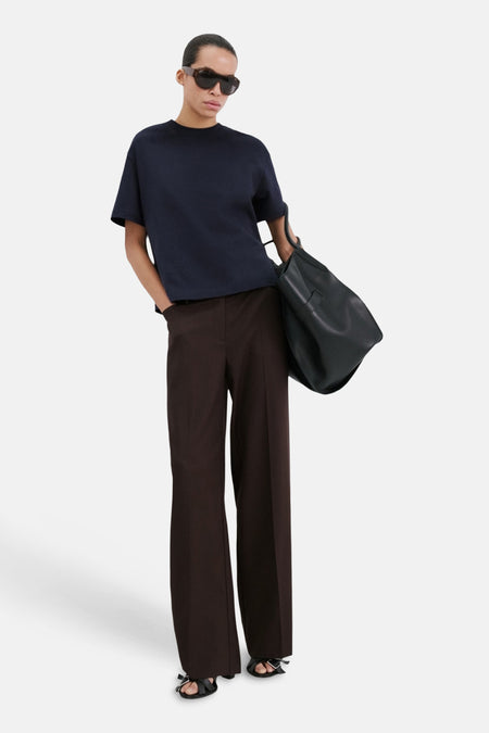 T-shirt bleu de MANGO, porté avec un pantalon marron et des sandales noires.
