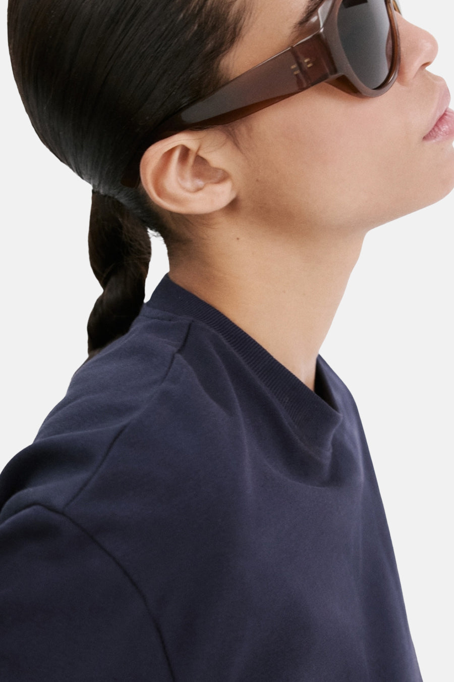 Blauw T-shirt van MANGO, ronde hals, gedragen met een bruine zonnebril en het haar naar achteren getrokken.