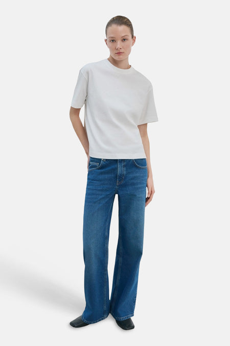 T-shirt blanc de MANGO, porté avec un jean bleu décontracté et des chaussures noires.