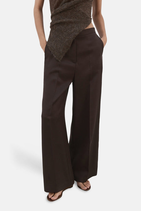 Pantalon brun, par MANGO, avec une coupe ample et jambes larges, porté avec un haut marron.
