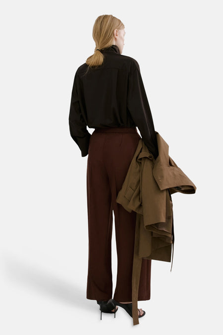 Pantalon brun de MANGO, coupe ample, porté avec une chemise noire et des talons.