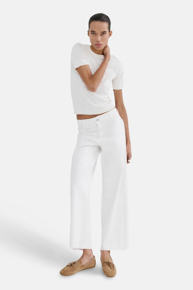 Jeans larges en denim blanc de MANGO, portés avec un t-shirt blanc et des chaussures bateau en cuir marron.