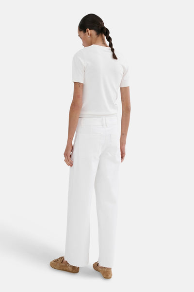 Jean large en denim blanc de Mango, vu de dos, porté avec un t-shirt blanc et des mocassins marron.