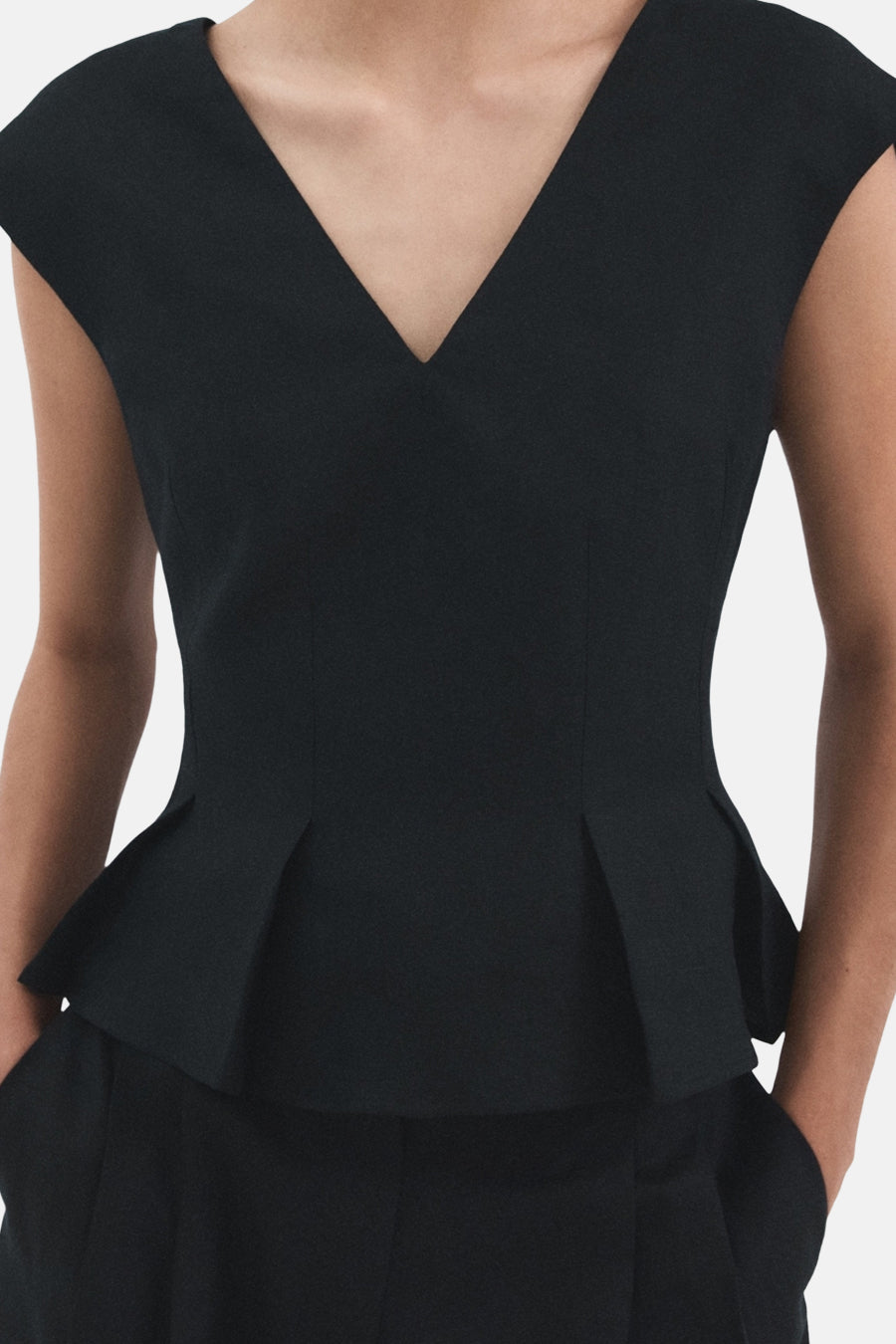Donkerblauwe mouwloze blouse van MANGO, met een V-hals en een peplum-pasvorm.