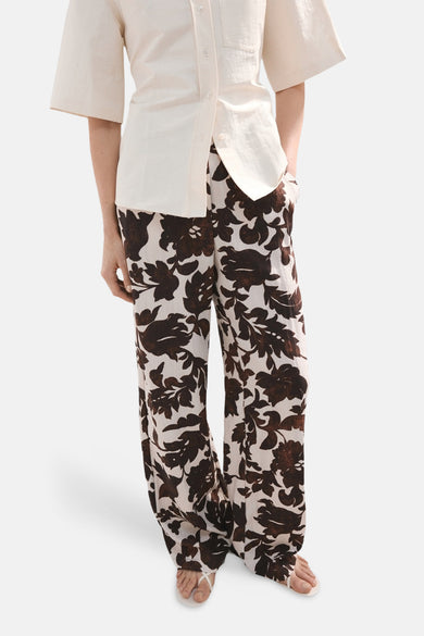 Pantalon multicolore de MANGO, à motif floral marron et blanc, porté avec une chemise claire.