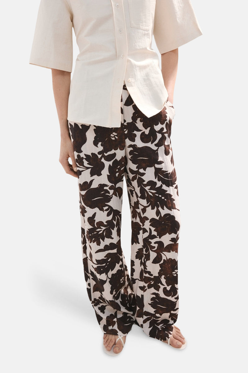 Pantalon multicolore de MANGO, à motif floral marron et blanc, porté avec une chemise claire.