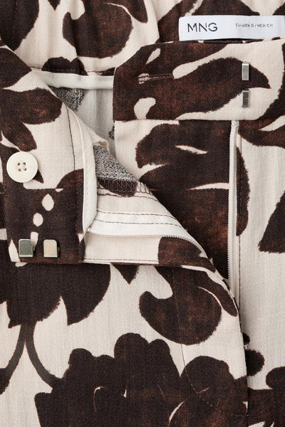 Pantalon multicolore par MANGO, avec un imprimé floral brun et blanc, et fermeture éclair.

