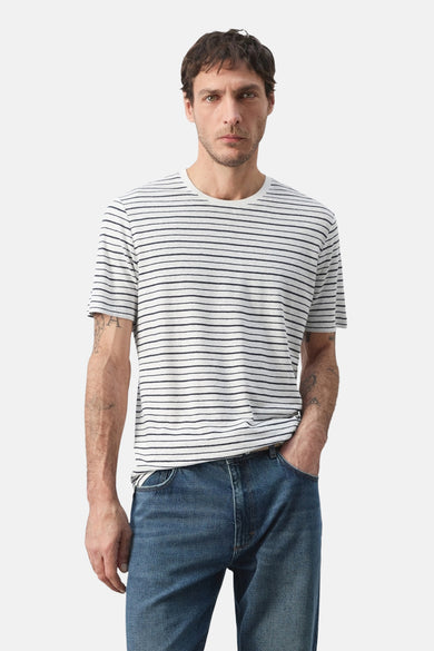 Multicolored striped short-sleeve t-shirt with round neckline, worn by model in front view with blue jeans.