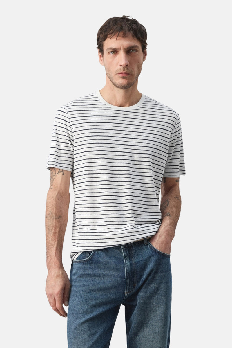 Multicolored striped short-sleeve t-shirt with round neckline, worn by model in front view with blue jeans.