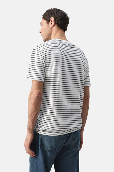 Multicolored striped short-sleeve t-shirt from back view, white base with thin black horizontal stripes, worn with blue jeans