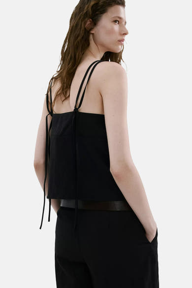 Top noir de MANGO à multiples fines bretelles nouées au dos, porté de dos par un mannequin avec un pantalon noir.