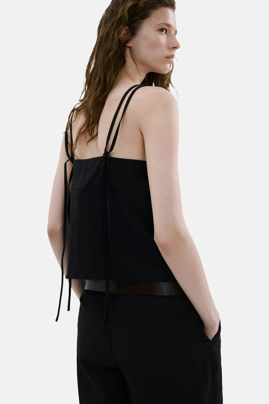 Top noir de MANGO à multiples fines bretelles nouées au dos, porté de dos par un mannequin avec un pantalon noir.