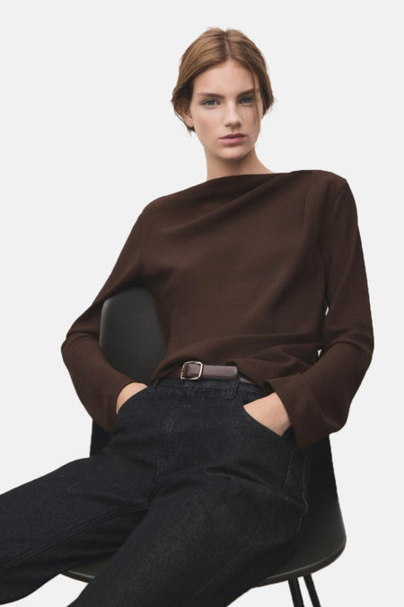 Blouse à manches longues brune de MANGO, portée avec un jean taille haute foncé et une ceinture marron.
